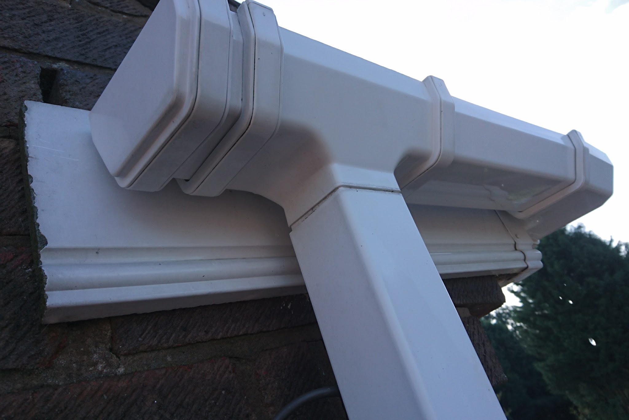 A spotless white uPVC gutter and downpipe junction after cleaning