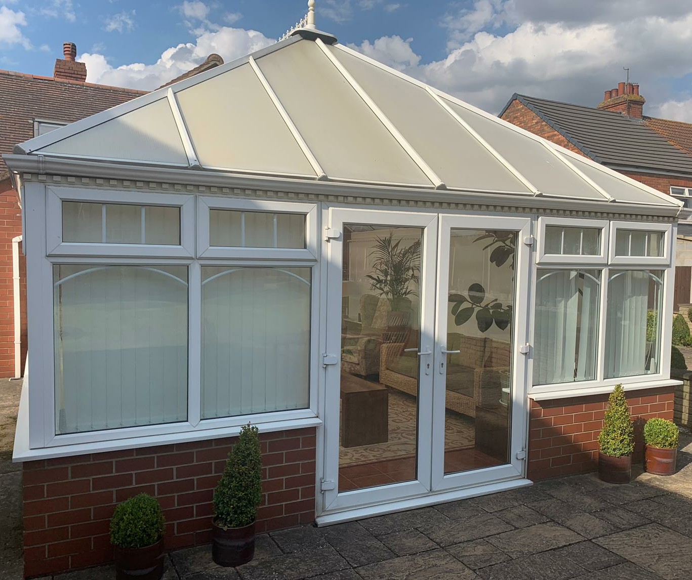 A conservatory with clean glass roof panels and white frames
