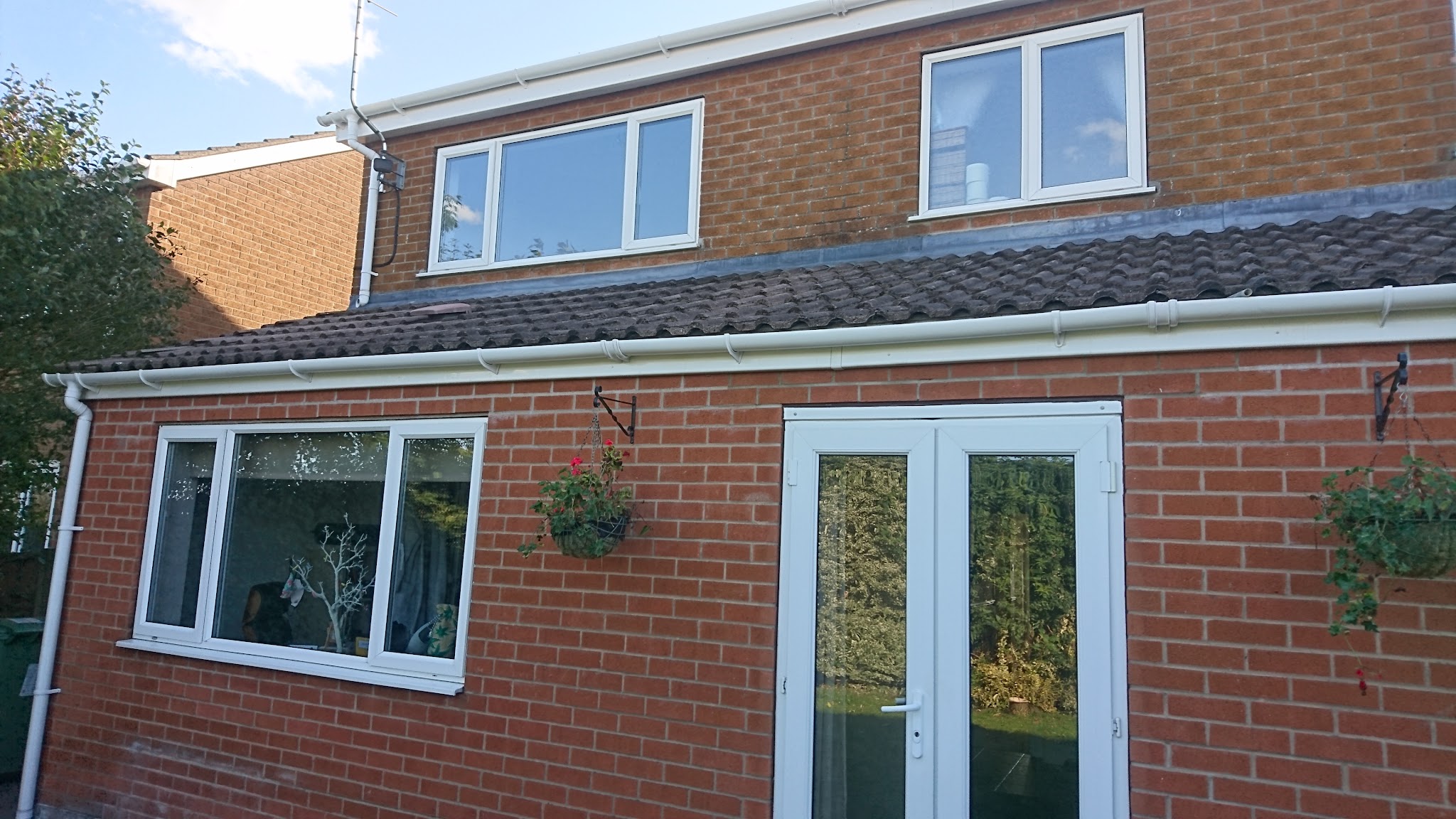 The rear of a brick house with clean white guttering, fascias and frames